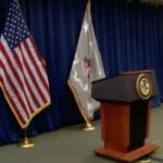 Coletiva de imprensa montada, com arquibancada vazia e bandeiras colocadas atrás. AGA emite declaração sobre investigação de jogo ilegal do FBI envolvendo estrelas da NBA