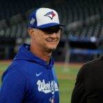 Don Mattingly usando um boné de beisebol azul e branco do Toronto Blue Jays, segurando o queixo.