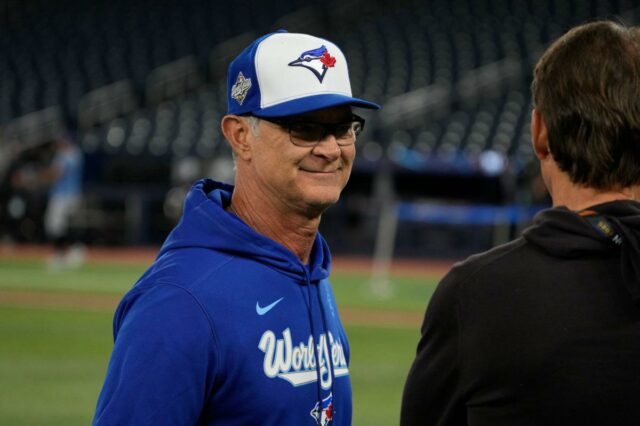 Don Mattingly se mostra tímido enquanto questões persistem sobre seu Don Mattingly usando um boné de beisebol azul e branco do Toronto Blue Jays, segurando o queixo.