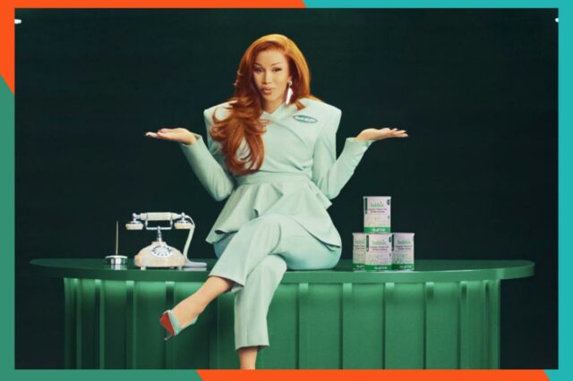 Empresa de fórmulas infantis reduz preços para famílias elegíveis para Uma mulher sorridente alimenta um bebê feliz com uma mamadeira, com um recipiente de Fórmula Infantil Orgânica Bobbie sobre a mesa.