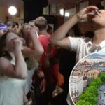 Pessoas em um pub rastejam bebendo shots.