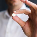 Man holding circular white pill