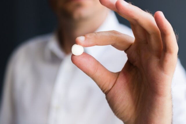 Man holding circular white pill