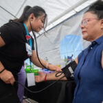 A enfermeira Haley Delgado, à esquerda, mede a pressão arterial de Maria Hernandez na Feira de Saúde e Recursos do Centro Médico Comunitário no Banner Island Ballpark, no centro de Stockton, Califórnia, em 9 de agosto de 2025.