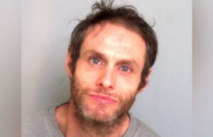 Homem é preso após eliminar traficante de drogas em batalha Um homem sorrindo para a câmera. Ele está lá dentro e vestindo uma camisa xadrez vermelha, azul e branca. Ele também está vestindo uma jaqueta azul marinho por cima