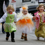 Três irmãs, cuja mãe solteira teme ser detida por engano por agentes federais de imigração porque é descendente de porto-riquenhos e fala espanhol, entram na Funston Elementary School depois de serem deixadas no início do dia letivo, no bairro de Logan Square, em Chicago, quarta-feira, 15 de outubro de 2025. (AP Photo/Rebecca Blackwell)