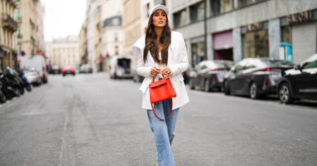 PARIS, FRANÇA - 04 DE NOVEMBRO: Emy Venturini usa óculos Gucci marrons, brincos de ouro, um pulôver de lã bege / creme oversized The Frankieshop como vestido, pulseiras, uma bolsa YSL de couro preto, sapatos / botas Toteme de couro preto pontiagudos, durante uma sessão de fotos de moda de estilo de rua, em 04 de novembro de 2024 em Paris, França. (Foto de Edward Berthelot/Getty Images)