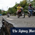 Os motoristas passam uma rachadura na estrada ao longo de uma grande estrada na província de Cebu causada pelo terremoto.