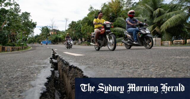 Os motoristas passam uma rachadura na estrada ao longo de uma grande estrada na província de Cebu causada pelo terremoto.