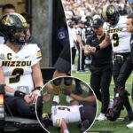O quarterback do Missouri, Beau Pribula (9), é auxiliado fora do campo pela equipe médica.