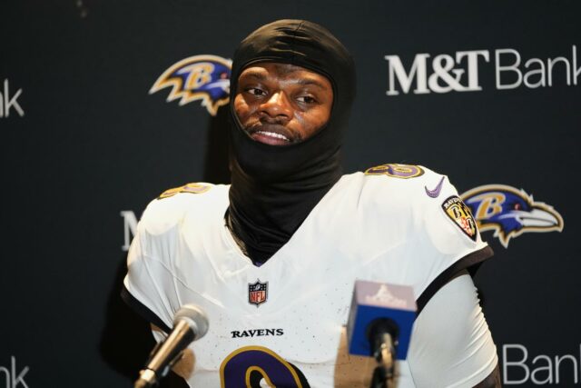 NFL multa Ravens em US$ 100 mil pelo fiasco da O jogador de futebol Lamar Jackson vestindo uma balaclava preta e uma camisa branca dos Ravens.
