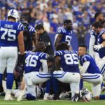 Indianapolis Colts players kneel around Spencer Shrader #3