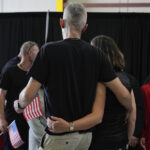 Jovens refugiados africâneres da África do Sul segurando bandeiras americanas chegam, segunda-feira, 12 de maio de 2025, ao Aeroporto Internacional de Dulles em Dulles, Virgínia. (AP Photo/Julia Demaree Nikhinson)