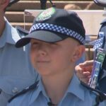 Bryson, de 12 anos, em um uniforme da polícia após seu dia Make-A-Wish, em colaboração com a polícia de NSW.