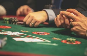 O povo do Golden State foi impedido de tomar medidas legais contra as salas de jogos por causa das liberdades civis únicas do estado Tribos da Califórnia foram impedidas de processar salas de jogos por direitos exclusivos do estado. Close de pessoas jogando pôquer em uma mesa de cassino, com cartas de baralho, fichas e mãos visíveis na superfície de feltro verde.