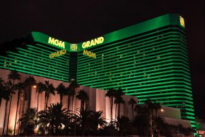O recorde monetário do terceiro trimestre da MGM Resorts permanece, Exterior do hotel MGM Grand em Las Vegas, uma luz verde brilhou no edifício. Palmeiras estão alinhadas na frente. O relatório financeiro do terceiro trimestre da MGM Resorts chegou, com a China vendo um aumento