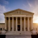 Juiz Federal envia Kalshi vs. Caso de Massachusetts volta ao tribunal estadual. A fachada frontal do edifício da Suprema Corte dos EUA ao pôr do sol, mostrando sua grande escadaria de mármore, altas colunas coríntias e esculturas detalhadas no frontão. A luz solar entra pelo lado direito, lançando um brilho quente em toda a cena, com árvores emoldurando a imagem em ambos os lados.