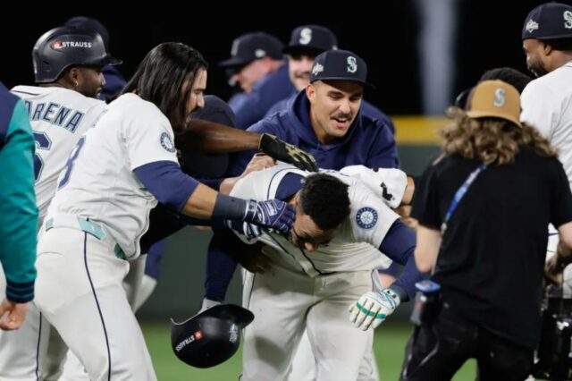 Jorge Polanco (centro) é assediado por companheiros de equipe depois de marcar uma única vitória no 15º turno da vitória dos Mariners sobre os Tigers no jogo 5 do ALDS em 10 de outubro de 2025.