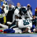 Jaxson Dart (6), do New York Giants, é abordado por Jalyx Hunt (58), do Philadelphia Eagles, e Kelee Ringo (7).