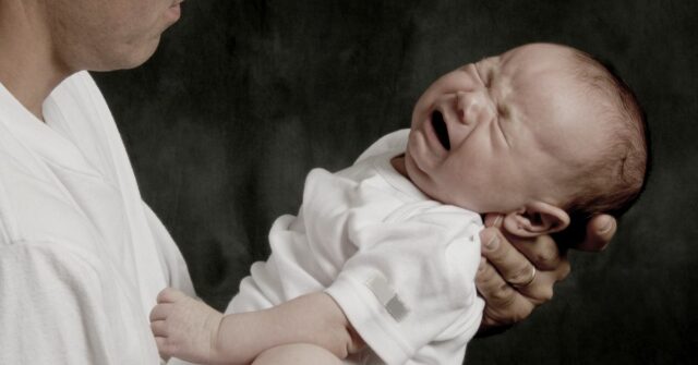 Um pai está segurando seu filho chorando.