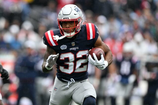 Mac Jones entregando a bola a um jogador do New England Patriots.