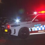 Carros da polícia da patrulha rodoviária de NSW estacionados em uma estrada à noite.