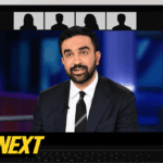 Zohran Mamdani no pódio com Kathy Hochul atrás dele.