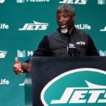 O técnico do New York Jets, Aaron Glenn, fala em um pódio.