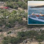 Um helicóptero vermelho pairando sobre uma encosta rochosa e coberta de arbustos.