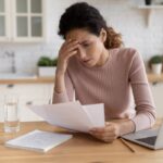 A young woman appears stressed while looking at her bills.