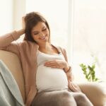 Mãe solteira asiática com síndrome das pernas inquietas e insônia à noite enquanto a filha dorme.