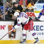 O New York Rangers Center, Vincent Trocheck, verifica o defensor de Boston Bruins, Andrew Peeke, nos quadros.