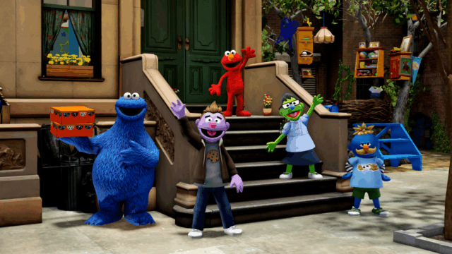Um jardim virtual 3D de cores vivas. Um avatar estilizado como um suporte de Muppet no centro.