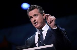 SGLA critica o Golden State Guv Newsom por autorizar restrição de sorteio ‘falha e apressada’ Califórnia Gavin Newsom em frente ao pódio vestindo terno. Governador da Califórnia, Newsom, criticado pelo SGLA por assinar a proibição de sorteios
