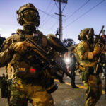 Um manifestante é preso pela polícia e oficiais federais do lado de fora de uma instalação de Imigração e Alfândega dos EUA em Portland, Oregon, segunda-feira, 6 de outubro de 2025. (AP Photo/Ethan Swope)