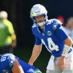 Matthew Stafford se preparando para lançar a bola de futebol enquanto Sam Okuayinonu se aproxima por trás.