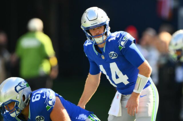 Matthew Stafford se preparando para lançar a bola de futebol enquanto Sam Okuayinonu se aproxima por trás.