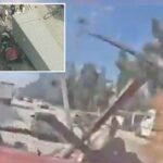 Vista aérea de uma cena de acidente de fogo envolvendo vários caminhões com destroços espalhados e uma pessoa com um colete laranja parada nas proximidades.