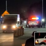 Um caminhão U-Haul dirige-se em direção a um veículo policial iluminado e policiais à noite.