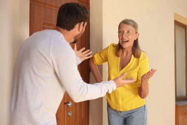 Neighbors having argument outside a door.