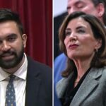 Zohran Mamdani falando em um pódio com Kathy Hochul olhando, sob uma faixa que diz