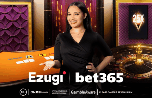 A bet365 faz parceria com a Ezugi para melhorar as ofertas de cassino ao vivo no Reino Unido, Ontário e Nova Jersey Uma sorridente dealer de cassino ao vivo está em frente a uma mesa de jogo laranja e uma roleta. Ela está usando um vestido preto e gesticula com uma das mãos em direção à mesa. O fundo apresenta painéis decorativos roxos e dourados e um gráfico multiplicador “25X” em uma tela. Os logotipos da Ezugi e da bet365 aparecem na parte inferior, junto com avisos de jogo responsável. A bet365 faz parceria com a Ezugi para melhorar as ofertas de cassino ao vivo no Reino Unido, Ontário e Nova Jersey