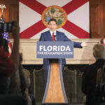 ARQUIVO - Uma estudante passa pela placa no New College of Florida, 20 de janeiro de 2023, em Sarasota, Flórida (AP Photo/Chris O'Meara, Arquivo)