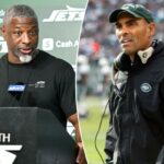 Herm Edwards, treinador do New York Jets, vestindo boné verde e jaqueta preta com o logotipo dos Jets.