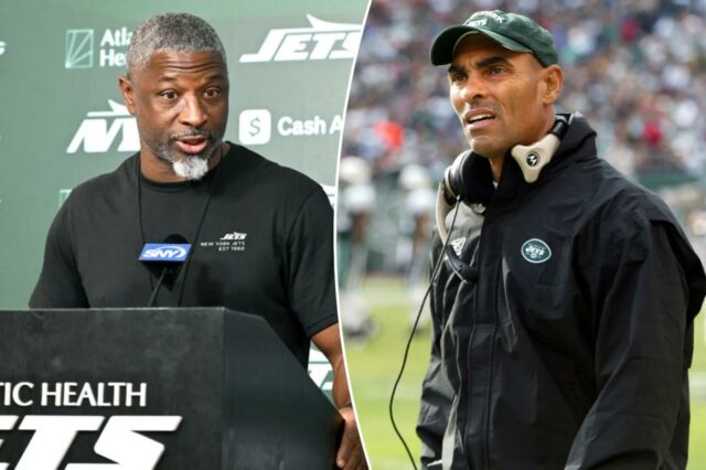 Herm Edwards, treinador do New York Jets, vestindo boné verde e jaqueta preta com o logotipo dos Jets.