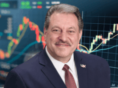 Addabbo deve abrir revisão legal em Nova York para potencialmente regular os mercados de previsão Addabbo abre revisão legal em Nova York para potencialmente regular os mercados de previsão. Um homem de terno azul-marinho e gravata vermelha sorri diante de um fundo que mostra gráficos financeiros coloridos e gráficos de velas.