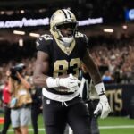 Um jogador da NFL com uniforme branco com número 88 e pintura no rosto grita.