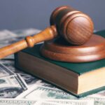 Apple buscando permissão para apelar de perda em processo de desenvolvedor de mais de US$ 1 bilhão | A foto mostra o martelo e o livro do tribunal em cima de uma pilha de notas de US$ 100