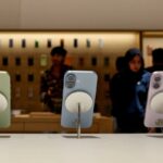 Três telefones iPhone 17, verde claro, azul claro e roxo claro, em exibição em uma loja da Apple.