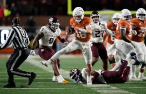 Arch Manning, Texas, estraga a tentativa da Texas A&M de uma temporada invicta para manter vivas as esperanças do CFP O quarterback do Texas Longhorns, Arch Manning, corre para um touchdown com um jogador do Texas A&M Aggies no chão.